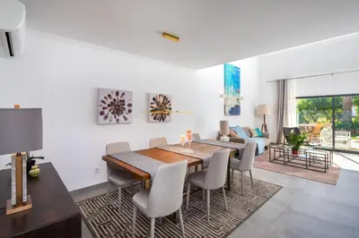 a dining room and living room with a table and chairs at Casa Relax à Olhos Albufeira in Albufeira