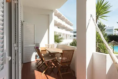 a balcony with a wooden table and chairs on a building at Alvaflor 102 - Vilamoura by HD Properties in Vilamoura