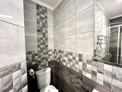 a bathroom with a toilet and a tiled wall at Quarteira Ocean Breeze 1 With Pool by Homing in Quarteira
