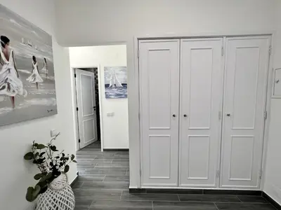 a hallway with white cabinets and a vase of flowers at Quarteira Ocean Breeze 1 With Pool by Homing in Quarteira