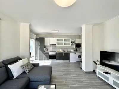 a living room with a couch and a kitchen at Quarteira Ocean Breeze 1 With Pool by Homing in Quarteira