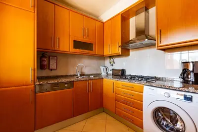 a kitchen with wooden cabinets and a washing machine at Casa Colina 2 in Albufeira