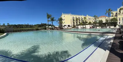 a large swimming pool in a resort with palm trees at Vilamoura Marina Lake in Vilamoura