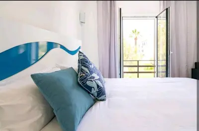 a bedroom with a white bed with blue pillows at Marina Holiday House in Quarteira