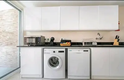a white kitchen with a washing machine in it at Marina Holiday House in Quarteira