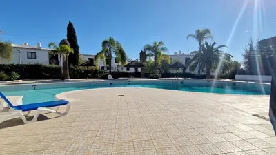a swimming pool with a chair next to a house at Sao Rafael T2 Duplex, Albufeira in Albufeira