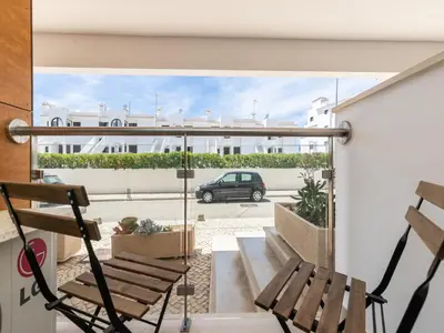 a balcony with two chairs and a car on a street at Akisol Olhos de Água Lyrical in Albufeira