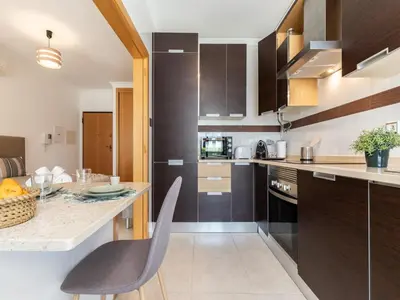 a kitchen with brown cabinets and a table and chairs at Akisol Olhos de Água Lyrical in Albufeira
