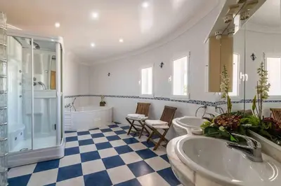 a bathroom with three sinks and a shower and a tub at Villa Cavi in Olhos de Água