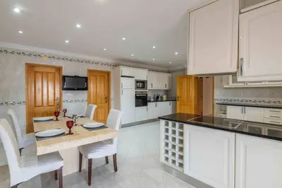 a large kitchen with white cabinets and a wooden door at Villa Cavi in Olhos de Água