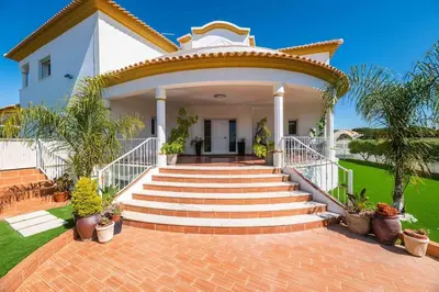 a large white house with a green lawn at Villa Cavi in Olhos de Água