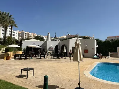 a pool with an umbrella next to a building at LV Apartment Albufeira in Albufeira