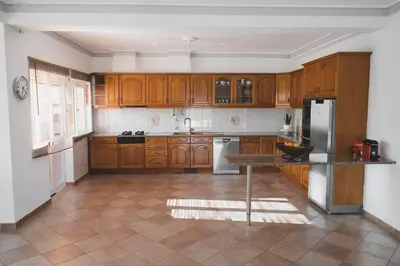 a kitchen with wooden cabinets and a refrigerator at Casa das Palmeiras - Villa com piscina, BBQ e ar condicionado in Albufeira