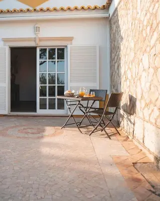 a table and chairs in front of a house at Casa das Palmeiras - Villa com piscina, BBQ e ar condicionado in Albufeira
