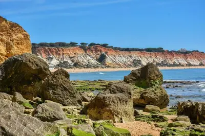a beach with rocks and the ocean and cliffs at Casa das Palmeiras - Villa com piscina, BBQ e ar condicionado in Albufeira