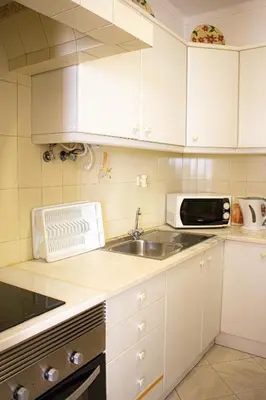 a kitchen with white cabinets and a sink and a microwave at Casa Maria in Albufeira
