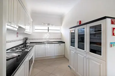 a kitchen with white cabinets and black counter tops at Yara Beach Apartments T1 in Albufeira