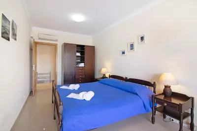 a bedroom with a blue bed with towels on it at Yara Beach Apartments T1 in Albufeira