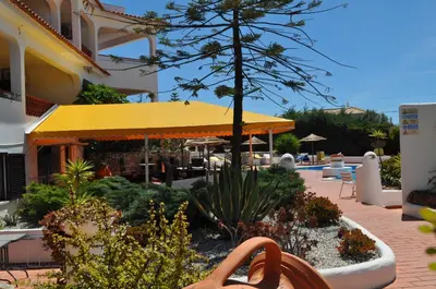 a patio with a yellow umbrella and some plants at Casa Areias Boutique Apartments in Albufeira