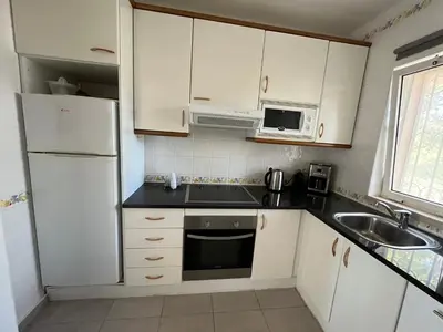 a kitchen with white cabinets and a sink and a refrigerator at House´s Golf in Almancil