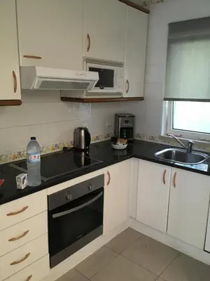 a kitchen with white cabinets and a black counter top at House´s Golf in Almancil