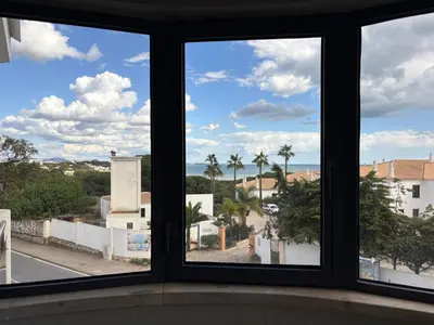 a window with a view of the ocean and palm trees at Coral By Albufeira Rental in Albufeira