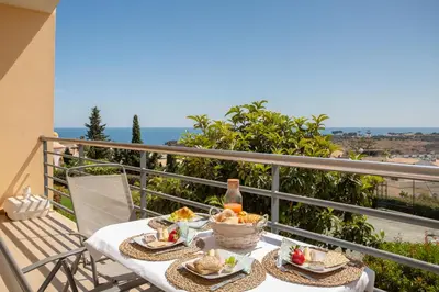 a table with food and a bottle of wine on a balcony at Encosta da Orada By Albufeira Rental in Albufeira