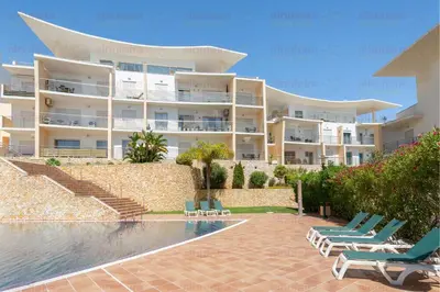 a large building with chairs and a swimming pool at Encosta da Orada By Albufeira Rental in Albufeira