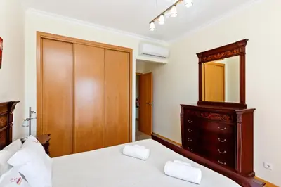 a bedroom with a bed and a dresser and a mirror at Encosta da Orada By Albufeira Rental in Albufeira