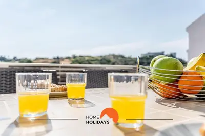 two glasses of orange juice and a bowl of fruit on a table at #164 Saradel 42 by Home Holidays in Albufeira