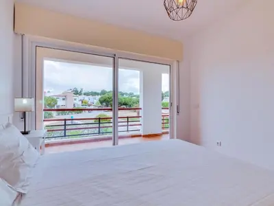 a bedroom with a white bed and a large window at AL - Apartamento Village Atlântico in Vilamoura