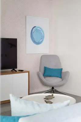 a living room with a chair and a television at Orange Boutique Residence - Casa Diogo in Quarteira
