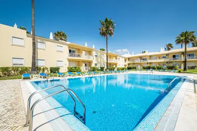 a swimming pool in a resort with chairs and palm trees at BeGuest Jardins Vale Parra Apartment in Albufeira
