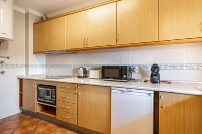 a kitchen with wooden cabinets and a counter top at BeGuest Jardins Vale Parra Apartment in Albufeira