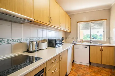 a kitchen with wooden cabinets and a counter top at BeGuest Jardins Vale Parra Apartment in Albufeira