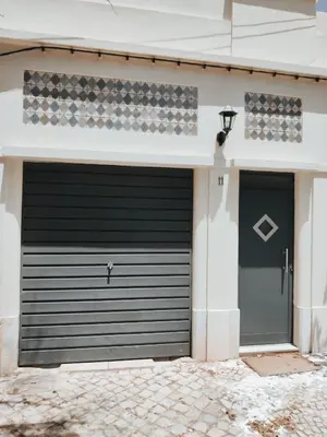 a black garage door on a white building at Wood11 - Charming TinyHouse in a Lovely Garden in Santa Bárbara de Nexe