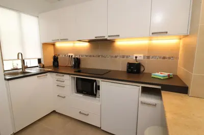 a kitchen with white cabinets and a black microwave at Camelia 52 Beach Studio Apartment - São Rafael, Albufeira in Albufeira