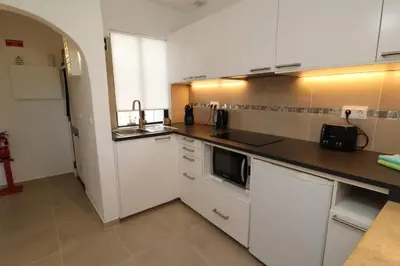 a kitchen with white cabinets and a black microwave at Camelia 52 Beach Studio Apartment - São Rafael, Albufeira in Albufeira
