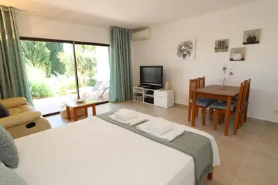 a bedroom with a bed and a table and a television at Camelia 52 Beach Studio Apartment - São Rafael, Albufeira in Albufeira
