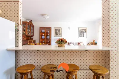 a kitchen with a counter with three wooden stools at #132 Velamar 414 by Home Holidays in Albufeira