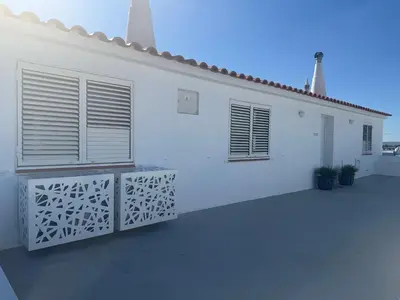 a white bedroom with two beds and a chair at Penthouse S.Jorge Seaview T4 in Quarteira