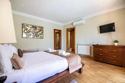 a bedroom with a bed and a tv on the wall at Villa Iris in Albufeira