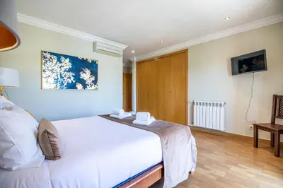 a bedroom with a white bed and a wooden door at Villa Iris in Albufeira