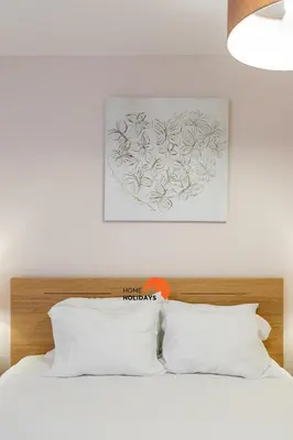 a bed with white pillows and a painting on the wall at #165 Liberdade 105 by Home Holidays in Albufeira