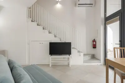 a living room with a television and a staircase at Madalena Village 1 - City centre by HD PROPERTIES in Faro
