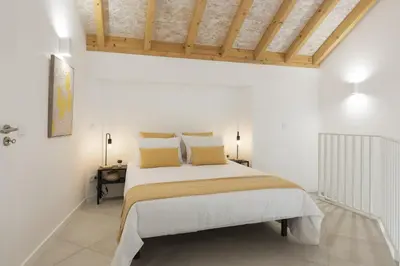 a bedroom with a large bed with white walls at Madalena Village 1 - City centre by HD PROPERTIES in Faro