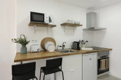 a kitchen with a counter with chairs and a sink at Madalena Village 4 - City centre by HD PROPERTIES in Faro