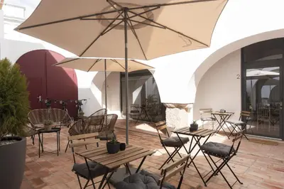 a patio with tables and chairs and an umbrella at Madalena Village 7 - City centre by HD PROPERTIES in Faro