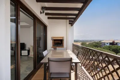 a balcony with a table and chairs and a fireplace at Elegance Apartment W/ Balcony & Pool by LovelyStay in Albufeira