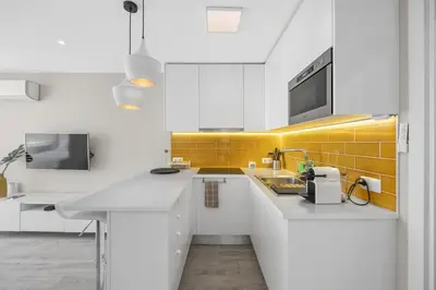 a kitchen with white cabinets and yellow tiles at Silver Lux Studio 1 - City Center by HD PROPERTIES in Vilamoura